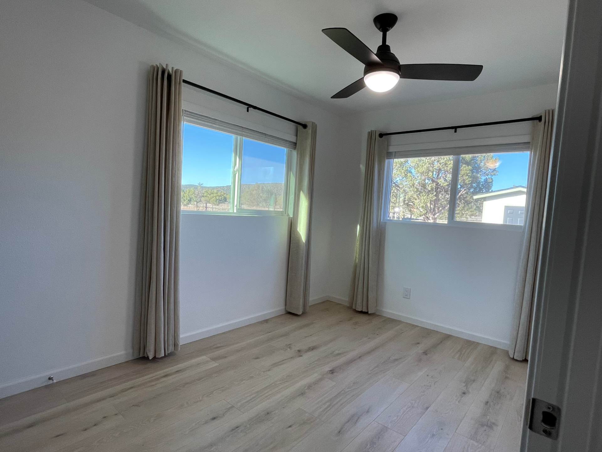 Empty bedroom with ceiling fan and curtains photographed with a phone